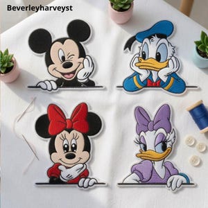 May include: Four embroidered fabric patches featuring classic cartoon characters. The top left shows a black and white mouse winking, the top right a white duck in a blue hat, the bottom left a mouse with a red bow, and the bottom right a white duck with a purple bow.