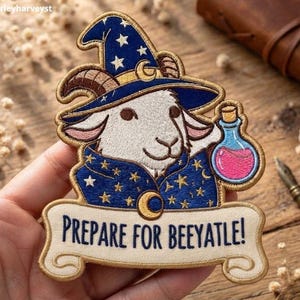 Peut inclure: Un écusson brodé représentant une chèvre blanche portant un chapeau et une cape de magicien bleu foncé ornés d'étoiles et de lunes dorées. La chèvre tient une petite fiole de potion bleue avec un liquide rose. Une bannière indique PREPARE FOR BEEYATLE!