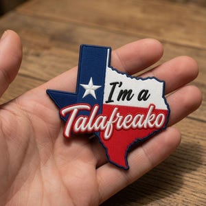 May include: An embroidered patch shaped like the state of Texas featuring the state flag colours of blue, white, and red with a white star. The text "I'm a" is printed in black, and the word "Talafreako" is embroidered in white with a red outline.