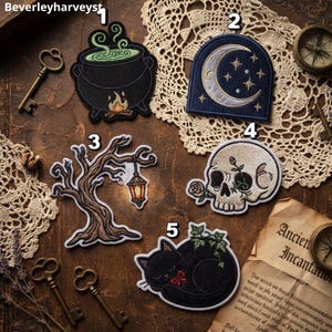 May include: Five embroidered patches featuring a black cauldron with green steam, a navy blue crescent moon with stars, a brown gnarled tree with a hanging lantern, a beige human skull with a rose, and a black cat with a red bow and green ivy.