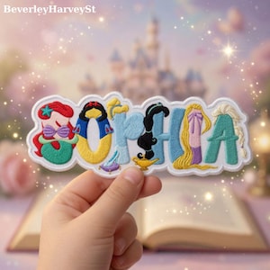 Peut inclure: Écusson brodé avec le nom "SOPHIA", chaque lettre étant conçue comme une princesse Disney. L'écusson comprend Ariel, Blanche-Neige, Jasmine, Raiponce et Elsa. L'écusson est blanc avec des broderies colorées.