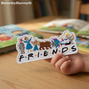 Peut inclure: Écusson brodé avec des personnages de dessins animés et le mot "FRIENDS". Le patch blanc présente des images d'un éléphant, d'une femme en robe bleue, d'une souris, d'un ours, d'un poisson et d'autres personnages.
