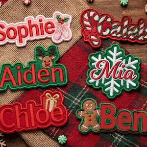 May include: Six embroidered name patches featuring festive designs: Sophie with ballet slippers, Caleb with a candy cane, Aiden with a reindeer, Mia with a snowflake, Chloe with a gift box, and Ben with a gingerbread man, all in red and green.