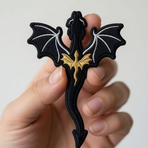 May include: Black embroidered dragon patch with white wing details and a gold dragon in the center. The patch has the text "BeverleyHarveySt" at the top. This patch is perfect for adding to clothing or accessories.