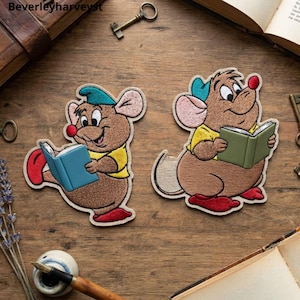 Peut inclure: Deux écussons brodés représentant des personnages de souris de dessin animé. Une souris porte une casquette bleu sarcelle et un haut jaune en lisant un livre bleu. L'autre porte une casquette bleu sarcelle et un haut jaune lisant un livre vert.