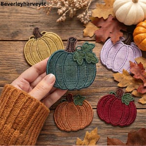May include: A collection of embroidered pumpkin patches in various colors including dark green, mustard yellow, light purple, orange, and deep red. Each patch features a brown stem and green leaves. The text Beverleyharveyst is visible.
