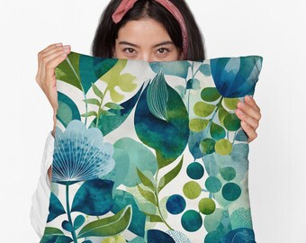 May include: A square decorative pillow with a watercolor floral design. The pillow features a pattern of blue, teal, and green leaves and flowers on a white background. The design includes various shapes and textures, creating a vibrant and artistic look.