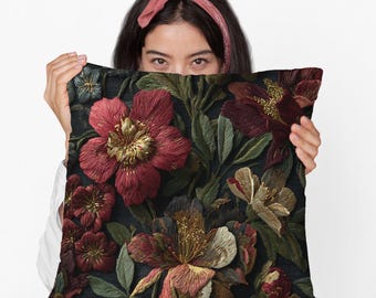 May include: Embroidered floral pillow featuring large, detailed flowers in shades of red, gold, and cream against a dark background. The pillow's design includes green leaves and intricate stitching, creating a textured, decorative accent.