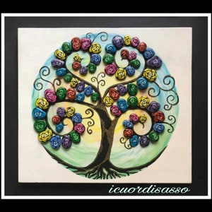 May include: A colorful tree made of painted stones in the shape of roses. The tree is painted on a white canvas with a blue and green background. The tree has a black trunk and branches with gold glitter accents. The text "icuordisasso" is at the bottom of the canvas.