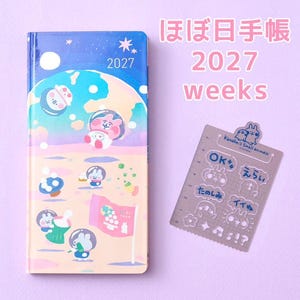 May include: A 2027 Hobonichi Weeks planner featuring a space-themed cover with cartoon animals in helmets on a peach-colored surface under a blue sky, alongside a clear plastic stencil sheet with Kanahei's Small animals and Japanese text.