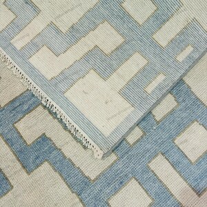 Handmade geometric wool rug styled in a modern interior setting with natural light. The abstract pattern and soothing color palette make this flatweave rug ideal for contemporary, Scandinavian, or coastal décor. Designed for both comfort and durability, this handwoven area rug enhances living rooms, bedrooms, or office spaces. Its clean design and artisan quality add a refined yet cozy touch to modern home interiors.