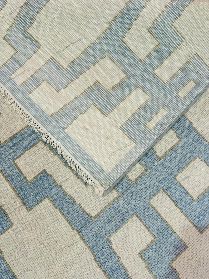 Handmade geometric wool rug styled in a modern interior setting with natural light. The abstract pattern and soothing color palette make this flatweave rug ideal for contemporary, Scandinavian, or coastal décor. Designed for both comfort and durability, this handwoven area rug enhances living rooms, bedrooms, or office spaces. Its clean design and artisan quality add a refined yet cozy touch to modern home interiors.