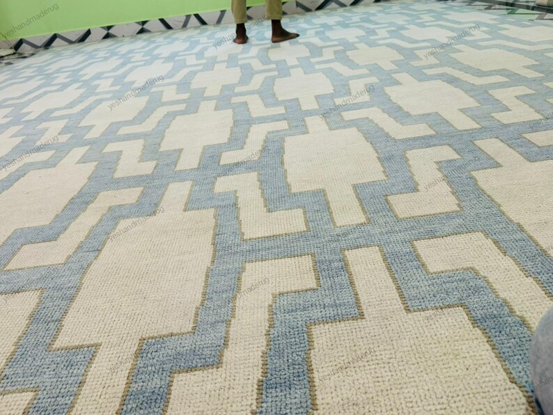 Side angle image showing the rug’s fringe detailing and clean woven finish. This handmade geometric rug features a durable flatweave structure and premium wool material. Its modern abstract design complements Scandinavian, coastal, and minimalist décor styles. Perfect as a living room or bedroom rug, this area rug brings artisan craftsmanship, subtle elegance, and timeless appeal to modern home décor settings.