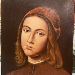 May include: A painting of a young person with long brown hair wearing a red hat and a brown jacket. The painting is signed "Pietro di Cristoforo  DAL PERUGINO".