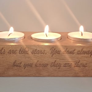 Op de afbeelding: Houten kaarsenhouder met drie kaarsvakken en de inscriptie "True friends are like stars, You don't always see them but you know they are there".
