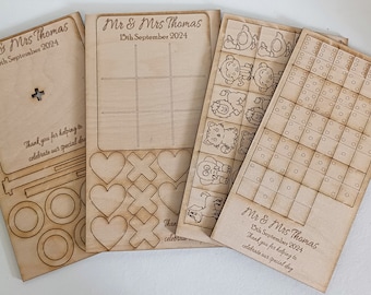 Könnte beinhalten: Vier Holzspielbretter mit Laser-geschnittenen Designs. Die Bretter sind für Tic-Tac-Toe, Connect Four, ein Memory-Spiel und ein Punkt-zu-Punkt-Spiel. Die Bretter sind mit dem Text "Mr. & Mrs. Thomas" und dem Datum "15. September 2024" personalisiert.