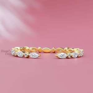 May include: A delicate gold band ring with a row of marquise-shaped diamonds. The ring is open on one side, making it adjustable.