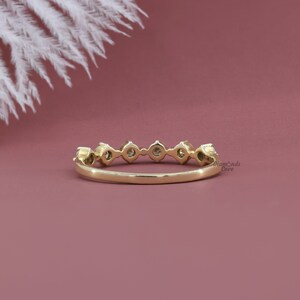 May include: A delicate gold band with a row of small round diamonds set in a pave setting. The band is simple and elegant, perfect for everyday wear.