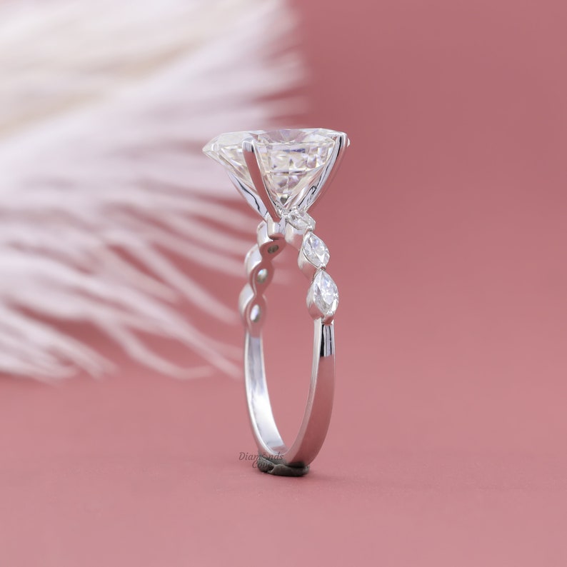May include: A silver engagement ring with a large, clear, round diamond center stone and smaller pear-shaped diamonds on the band.