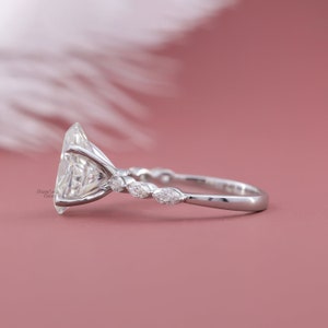 May include: A silver engagement ring with a large, clear, oval-shaped center stone and smaller, clear, marquise-shaped stones set in a delicate band.