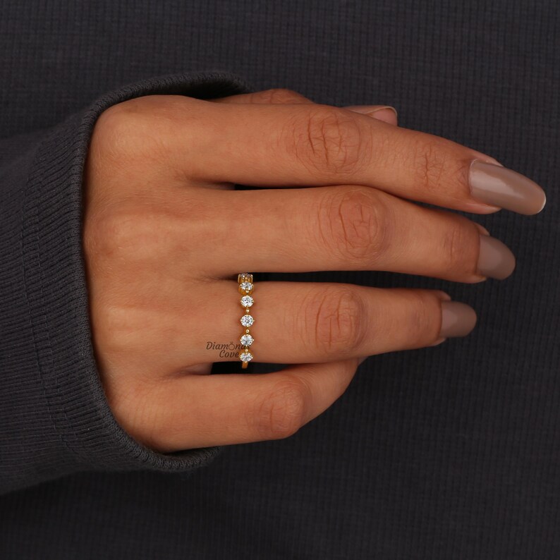 May include: A gold band ring with a row of small, clear round stones.