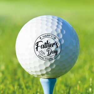 May include: White golf ball with a black circle sticker that says "Happy Father's Day 2024 Love, Harry" on it.