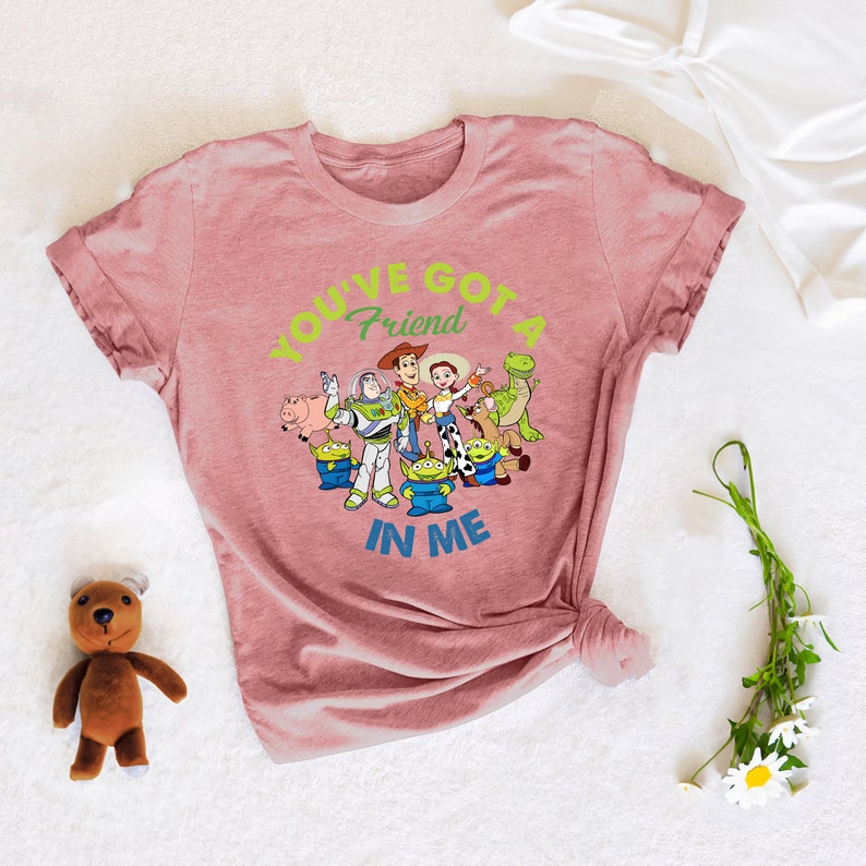 May include: A pink t-shirt featuring a graphic of the Toy Story characters and the text "You've Got a Friend in Me".