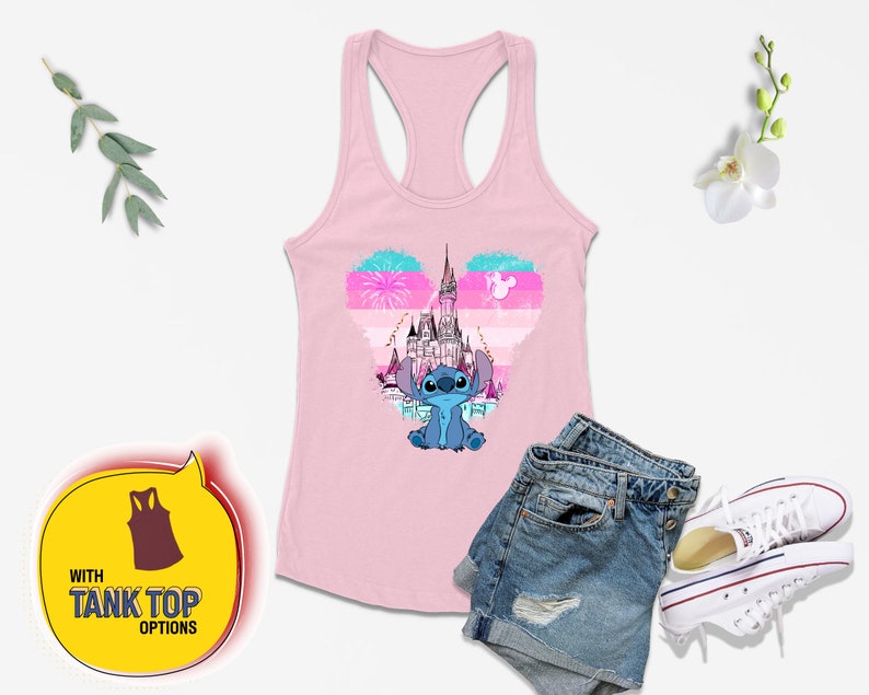 Op de afbeelding: Een roze tanktop met een blauw Stitch-personage en een roze, blauw en wit hartvormig ontwerp met het kasteel van Assepoester. Het ontwerp bevat ook vuurwerk en een silhouet van Mickey Mouse.