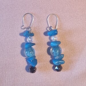 May include: A pair of dangle earrings with blue and clear glass beads and silver hooks.