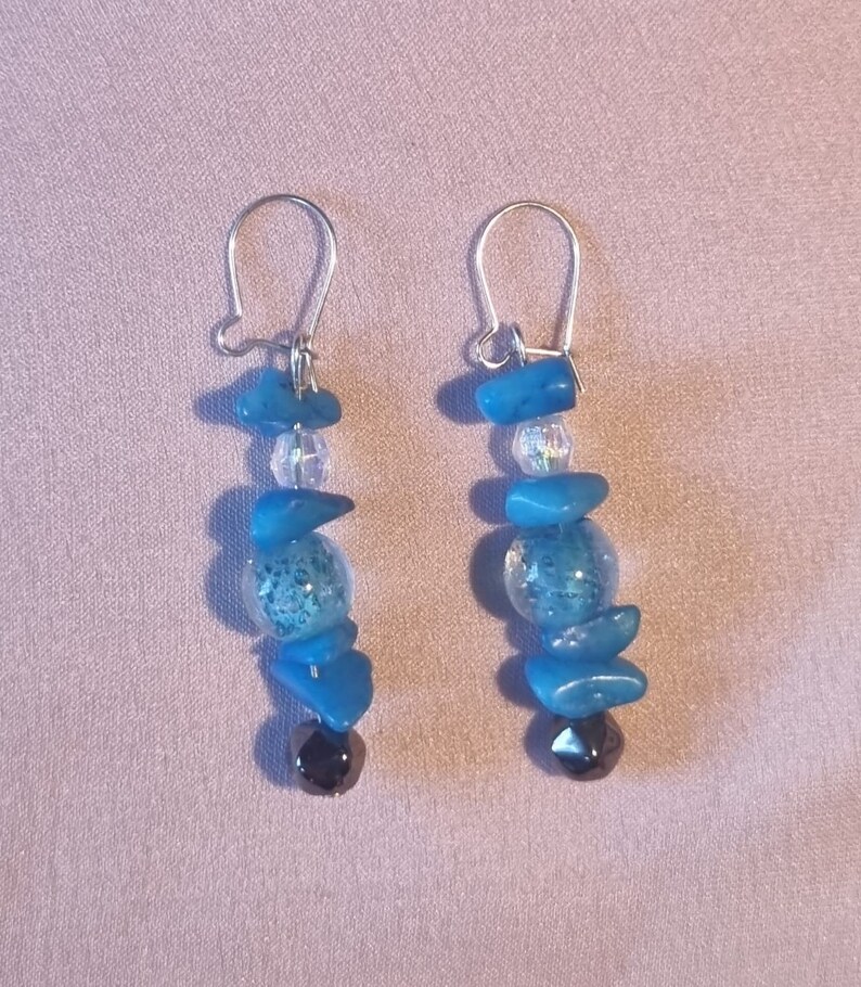 May include: A pair of dangle earrings with blue and clear glass beads and silver hooks.