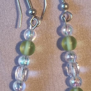 May include: A pair of silver dangle earrings with green and clear glass beads.