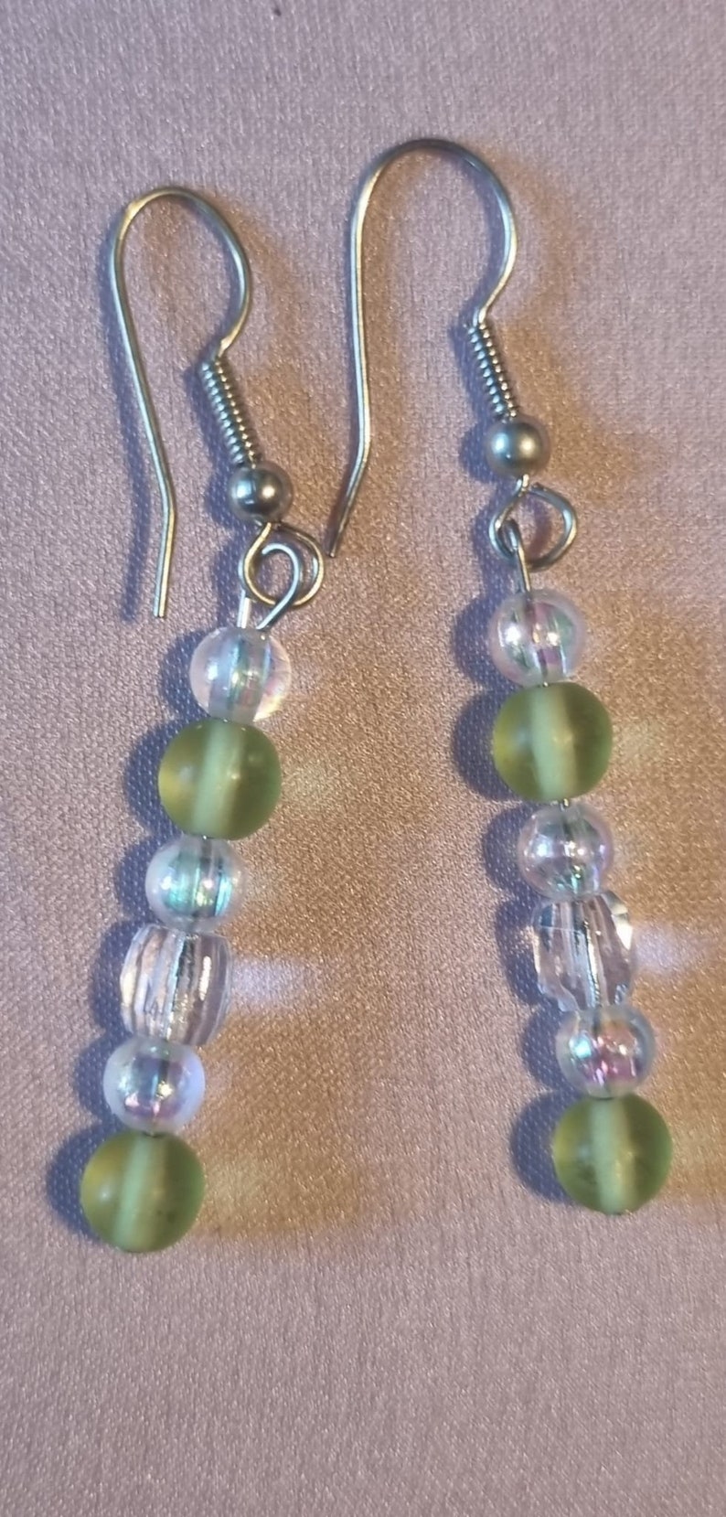 May include: A pair of silver dangle earrings with green and clear glass beads.