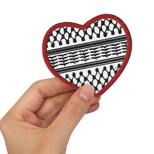 May include: A red heart-shaped patch with a black and white pattern. The pattern is a traditional Palestinian keffiyeh design.