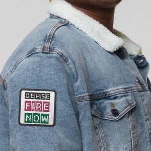 May include: A blue denim jacket with a sherpa collar and a patch on the left sleeve that says "CEASE FIRE NOW" in black, red, and green.