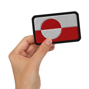 May include: A rectangular patch featuring the flag of Greenland. The design includes a white and red color scheme with a large circle divided into two halves. The patch has a black border.