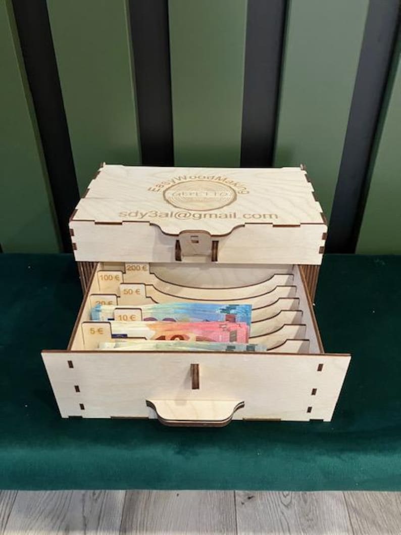 May include: Wooden box with a drawer for storing cash. The box has slots for bills of different denominations, including 5 euro, 10 euro, 50 euro, 100 euro, and 200 euro. The box is labeled "Easy Wood Making" and includes the email address "sdy3al@gmail.com".