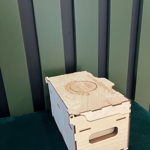 May include: A wooden box with a hinged lid and a handle. The box is made of light wood and has a laser-engraved logo on the top that reads "EASYWOOD Making Your Ideas Real".