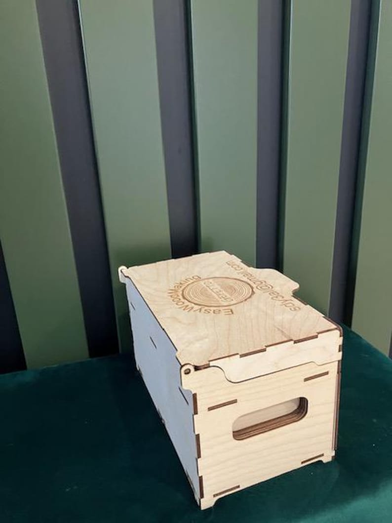 May include: A wooden box with a hinged lid and a handle. The box is made of light wood and has a laser-engraved logo on the top that reads "EASYWOOD Making Your Ideas Real".