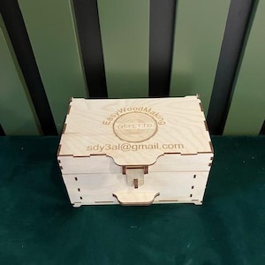 May include: A wooden box with a hinged lid and a latch. The box is engraved with the text "Easy Wood Making" and a logo. The text "sdy3al@gmail.com" is also engraved on the box.