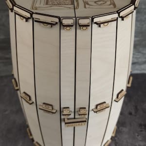 Könnte beinhalten: Eine Holzkiste in Fassform mit einem Scharnierdeckel. Der Deckel zeigt ein lasergraviertes Design einer Whiskyflasche und eines Glases mit Eiswürfeln. Die Kiste hat ein Etikett mit der Aufschrift "WHISKEY".