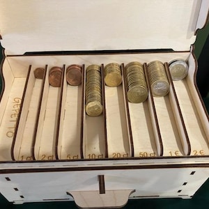 May include: Wooden coin box with eight compartments for sorting coins. The compartments are labeled with the denominations: 1c, 2c, 5ct, 10ct, 20ct, 50ct, 1&euro;, and 2&euro;. The box is labeled "GEPETTO".