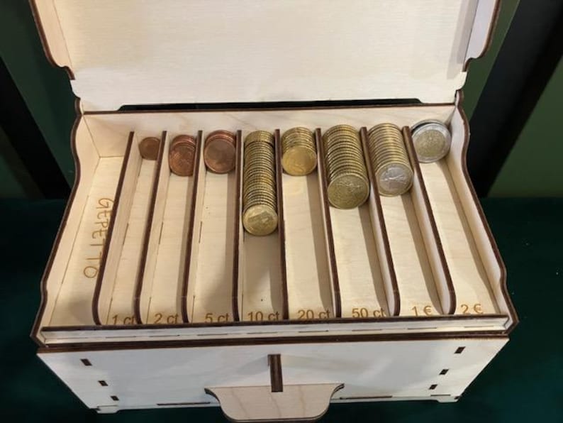 May include: Wooden coin box with eight compartments for sorting coins. The compartments are labeled with the denominations: 1c, 2c, 5ct, 10ct, 20ct, 50ct, 1&euro;, and 2&euro;. The box is labeled "GEPETTO".