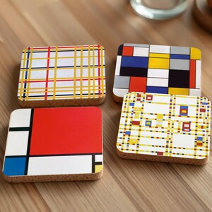 Op de afbeelding: Vier vierkante onderzetters met verschillende geometrische patronen. De onderzetters zijn gemaakt van kurk en hebben verschillende kleuren, waaronder rood, geel, blauw en zwart.