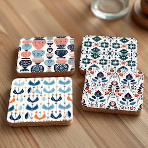 Op de afbeelding: Vier vierkante kurk onderzetters met verschillende geometrische en bloemmotieven in tinten blauw, wit en oranje.