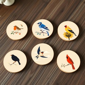 May include: Six round coasters with a cream background and colorful bird illustrations. Each coaster features a different bird species, including a blue jay, a robin, a cardinal, a blackbird, a swallow, and a goldfinch.