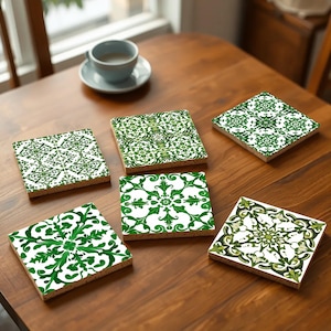 Könnte beinhalten: Sechs Untersetzer aus Kork mit quadratischer Form und einem floralen Muster in Grün und Weiß.