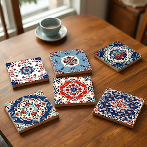 Può includere: Sei sottobicchieri in ceramica colorati con intricati motivi geometrici in tonalità di blu, rosso e bianco. I sottobicchieri sono disposti su un tavolo di legno.