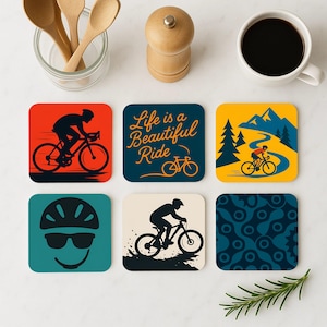 Pode incluir: Conjunto de seis  tapetes quadrados com tema de ciclismo. Os tapetes têm diferentes designs, incluindo um ciclista a andar de bicicleta, uma cena de montanha, um padrão de corrente de bicicleta e o texto "Life is a Beautiful Ride".