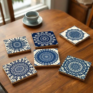May include: Six blue and white ceramic coasters with intricate mandala designs. The coasters are arranged on a wooden table.