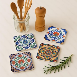 May include: Four square ceramic coasters with colorful floral patterns. The coasters feature blue, orange, and yellow designs. Wooden spoons, a fork, and a pepper grinder are also in the image.
